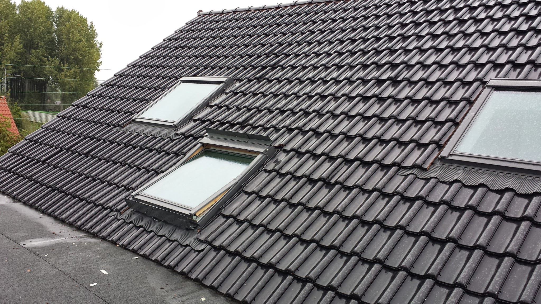 Artisan couvreur r&eacute;alisant la pose de tuiles sur une toiture neuve